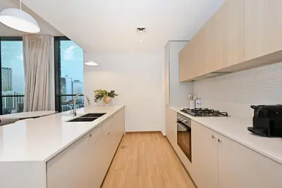 a kitchen with white counters and a large window at Belgravia Heights 1 BHK in JVC in Dubai