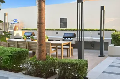 a patio with a table and chairs and a palm tree at Belgravia Heights 1 BHK in JVC in Dubai