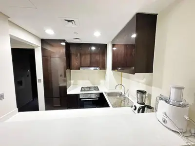 a kitchen with wooden cabinets and a white counter top at Merano Tower 1BHK in Business Bay By Petals Holiday Homes in Dubai