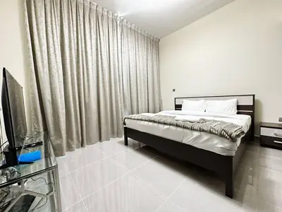 a bedroom with a bed and a tv and curtains at Merano Tower 1BHK in Business Bay By Petals Holiday Homes in Dubai