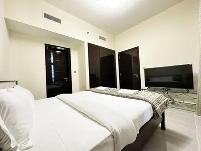 a bedroom with a large bed and a flat screen tv at Merano Tower 1BHK in Business Bay By Petals Holiday Homes in Dubai