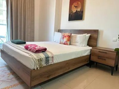 a bedroom with a large bed with a wooden frame at Comfortable Studio Retreat in Dubai Sports City in Dubai