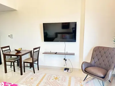 a living room with a table and chairs and a tv at Comfortable Studio Retreat in Dubai Sports City in Dubai
