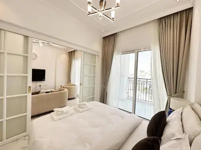 a bedroom with a large white bed and a living room at Vincitore Benessere 1BHK in Arjan by Petals Holiday Homes in Dubai