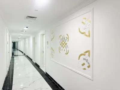 a hallway with white walls and gold paintings on the wall at Vincitore Benessere 1BHK in Arjan by Petals Holiday Homes in Dubai