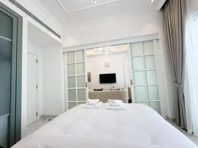 a white bedroom with a large bed with two towels at Vincitore Benessere 1BHK in Arjan by Petals Holiday Homes in Dubai