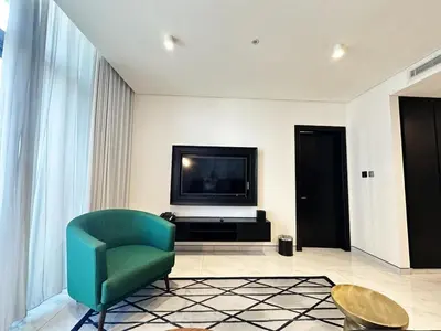 a living room with a green chair and a television at Elegant 1BR in Business Bay in Dubai