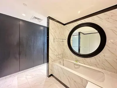 a bathroom with a tub and a round mirror at Elegant 1BR in Business Bay in Dubai