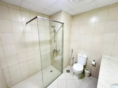 a bathroom with a toilet and a glass shower at Profile Residency Studio near Dubai Stadium by Petals Holiday Homes in Dubai