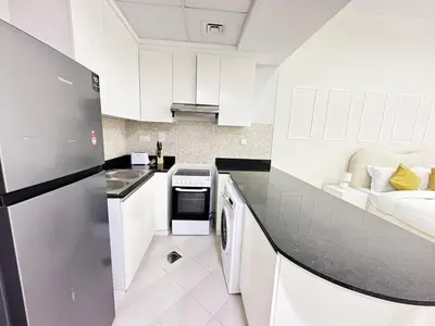 a kitchen with white cabinets and a black counter top at Profile Residency Studio near Dubai Stadium by Petals Holiday Homes in Dubai