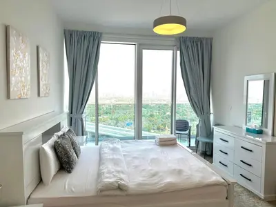 a bedroom with a large bed with a large window at 1 Residence 1BHK near Metro by Petals Holiday Homes in Dubai