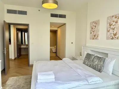 a bedroom with a white bed and a bathroom at 1 Residence 1BHK near Metro by Petals Holiday Homes in Dubai