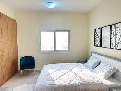 a bedroom with a bed and a blue chair at Cordoba Palace Studio In Silicon Oasis by Petals Holiday Homes in Dubai