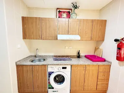 a kitchen with a washing machine and a sink at Cordoba Palace Studio In Silicon Oasis by Petals Holiday Homes in Dubai