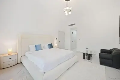 a white bedroom with a white bed and a black chair at 5 BR Villa Near Business Bay By Petals Holiday Homes in Dubai