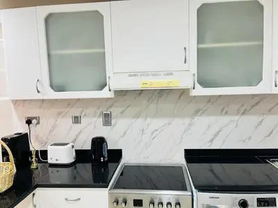 a kitchen with white cabinets and a stove top at Indigo Tower 1 BR in JLT by Petals Holiday Homes in Dubai