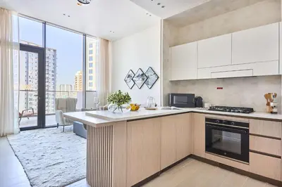 a kitchen with white cabinets and a large window at Frank Porter - Binghatti Phantom in Dubai
