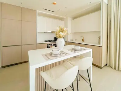 a kitchen with a white island with white chairs at Binghatti Aurora Soft-Luxe 1BR Abode w Gym & Pool in Dubai