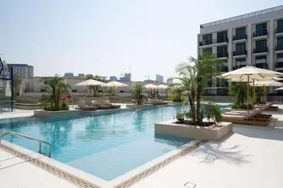 a large swimming pool with chairs and umbrellas on a building at Binghatti Aurora Soft-Luxe 1BR Abode w Gym & Pool in Dubai