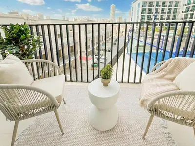 a balcony with two chairs and a plant on a table at Binghatti Aurora Soft-Luxe 1BR Abode w Gym & Pool in Dubai