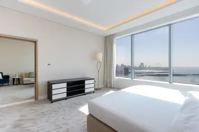 a white bedroom with a bed and a large window at Luxury 1BR on Palm Jumeirah with Pool Access and Beach in Dubai
