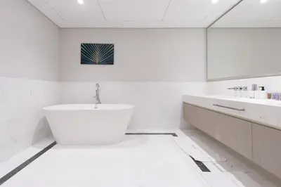 a white bathroom with a tub and a sink at Luxury 1BR on Palm Jumeirah with Pool Access and Beach in Dubai