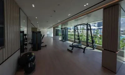 a gym with cardio equipment in a building with windows at Warm Modern 1BR Haven with Balcony & Free Parking in Dubai