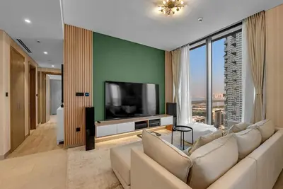 a living room with a large couch and a television at Waves - Elegant High-Floor 2BR Close To Downtown in Dubai