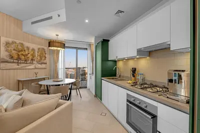 a kitchen and living room with a couch and a table at Waves - Elegant High-Floor 2BR Close To Downtown in Dubai