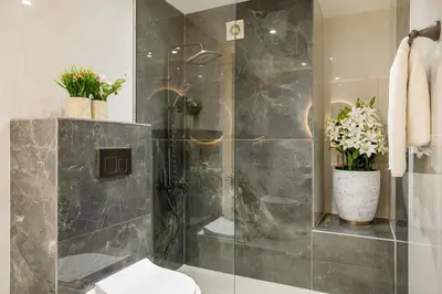 a bathroom with a shower with a vase of flowers at Stylish 2BHK Central Marina Rooftop Pool DEC T1 601 in Dubai