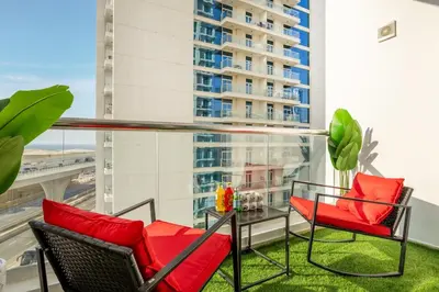 a balcony with two chairs and a table with red pillows at Stylish 2BHK Central Marina Rooftop Pool DEC T1 601 in Dubai