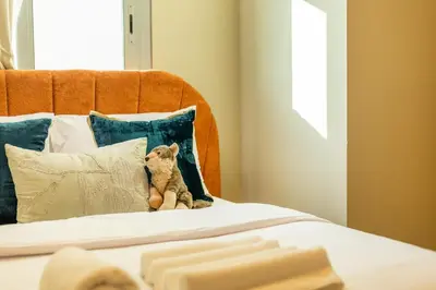 a teddy bear sitting on a bed with pillows at Luxury 2BHK w Floating Bed in Dubai Marina DEC 1604 in Dubai