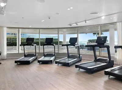 a gym with a row of treadmills and windows at Luxury one bed flat in Dubai Harbour in Dubai