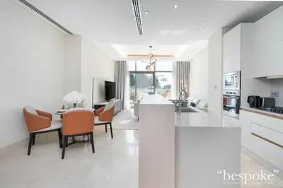 a kitchen and living room with a table and chairs at Bespoke Holiday Homes - Elegant 2BR with Terrace in The 8 Palm Jumeirah in Dubai