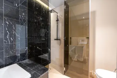 a bathroom with a glass shower with a toilet at Bespoke Holiday Homes - Elegant 2BR with Terrace in The 8 Palm Jumeirah in Dubai