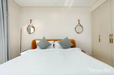 a bedroom with a large white bed with blue pillows at Bespoke Holiday Homes - Elegant 2BR with Terrace in The 8 Palm Jumeirah in Dubai