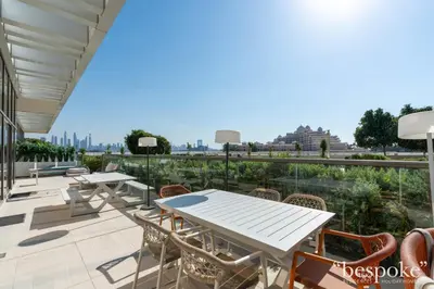 a patio with tables and chairs and a view of the city at Bespoke Holiday Homes - Elegant 2BR with Terrace in The 8 Palm Jumeirah in Dubai