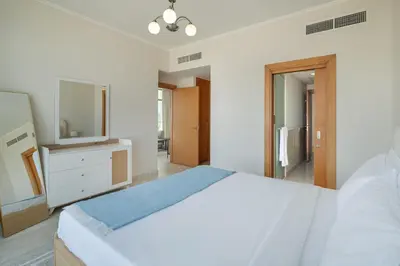 a white bedroom with a large bed and a television at Greens Haven City & Golf View Balcony in Dubai