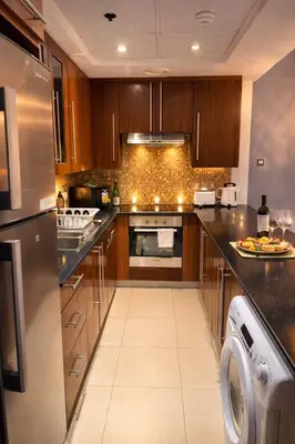 a kitchen with wooden cabinets and a washer and dryer at Cozy Studio in Downtown, Short walk to Burj Khalifa in Dubai