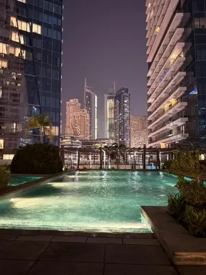 a large swimming pool in a city at night at Elegant Studio, Marina access, Queen & Sofabed in Dubai