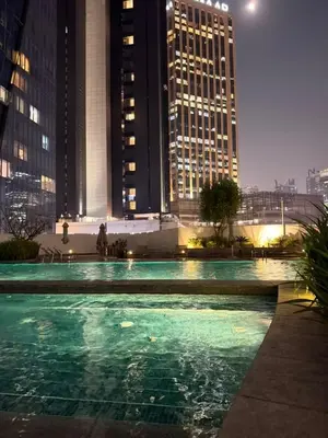 a large swimming pool in a city at night at Elegant Studio, Marina access, Queen & Sofabed in Dubai