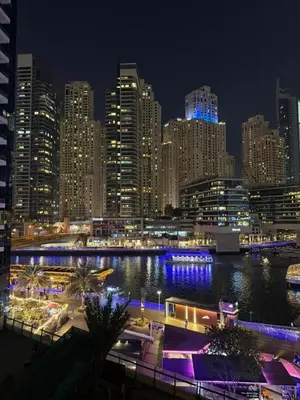 a city skyline at night with a river and buildings at Elegant Studio, Marina access, Queen & Sofabed in Dubai