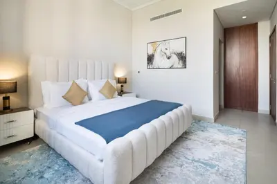 a white bedroom with a large bed with a blue blanket at Rare 4BR Vida Golf & Pool View in Dubai