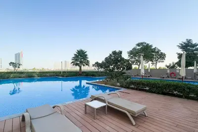 a swimming pool with two lounge chairs on a wooden deck at Rare 4BR Vida Golf & Pool View in Dubai