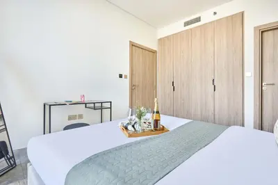 a bedroom with a white bed with a bottle of champagne at Frank Porter - Peninsula One in Dubai