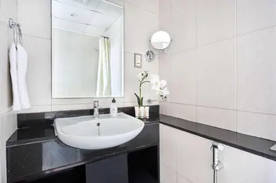 a white bathroom with a sink and a mirror at Frank Porter - Damac Ghalia in Dubai