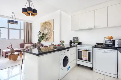 a kitchen with white cabinets and a washer and dryer at Frank Porter - Damac Ghalia in Dubai