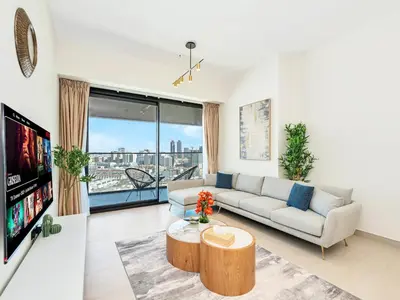 a living room with a couch and a tv at Premium 2BD with Balcony Pool & Gym in Dubai