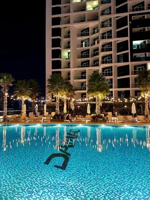 a swimming pool with chairs and a building at night at Premium Studio Burj Khalifa & Canal View in Dubai