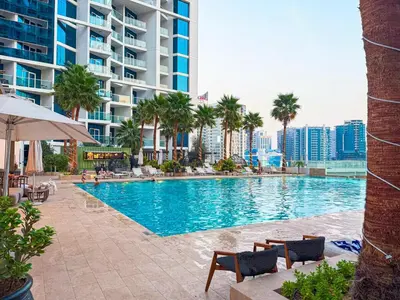 a swimming pool with chairs and palm trees and a building at Premium Studio Burj Khalifa & Canal View in Dubai